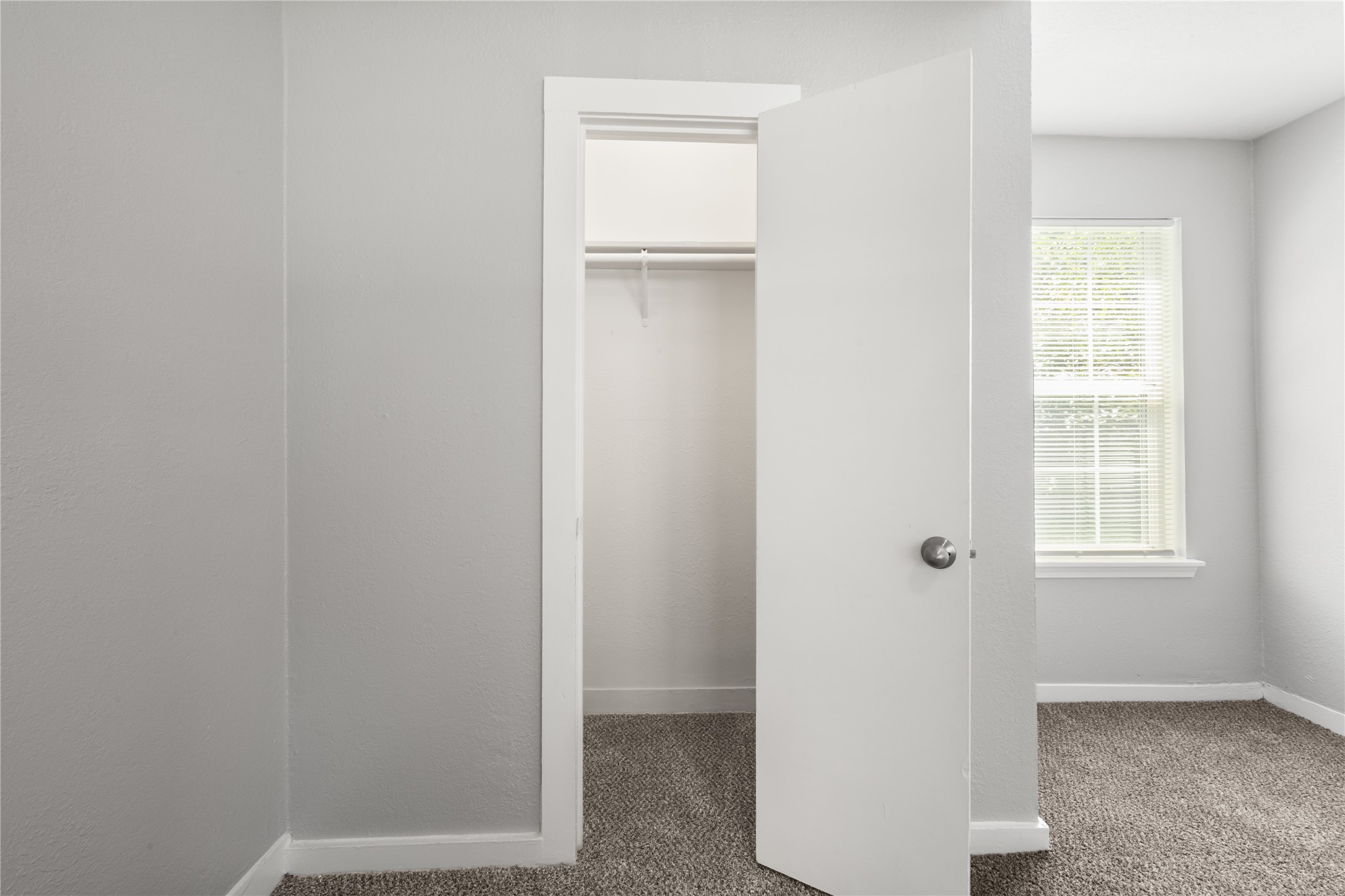 9210 Compton Street Houston, TX 77016 - Photo 9 of 50 Cozy room featuring a small closet with a white door, complemented by soft carpet flooring and a window allowing natural light to brighten the space.