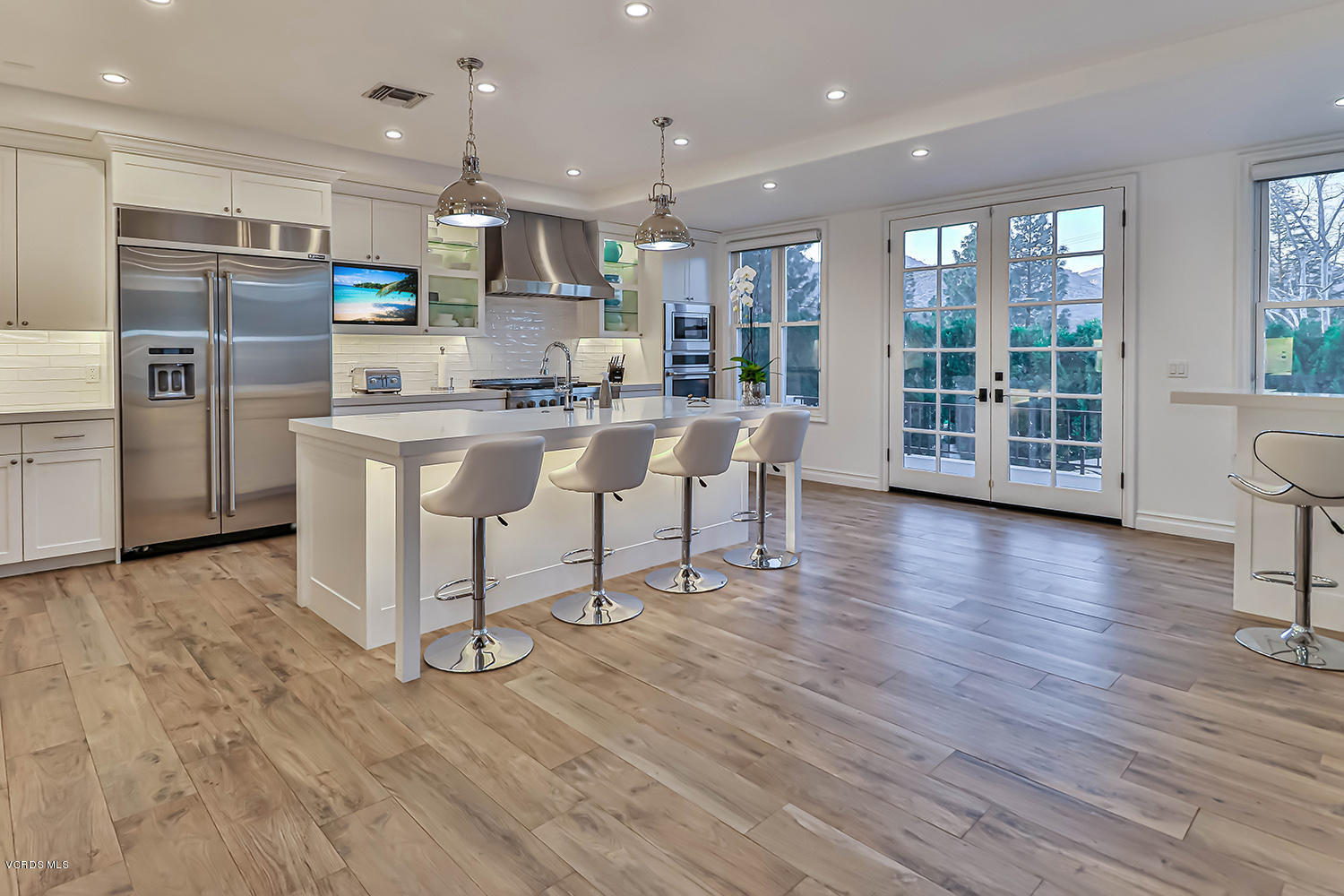 22457 North Summit Ridge Circle Chatsworth, CA 91311 - Photo 16 of 63 a kitchen with stainless steel appliances granite countertop a stove a refrigerator a sink a dining table and chairs with wooden floor