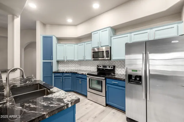 a kitchen with stainless steel appliances granite countertop a refrigerator a stove and a sink with wooden floor