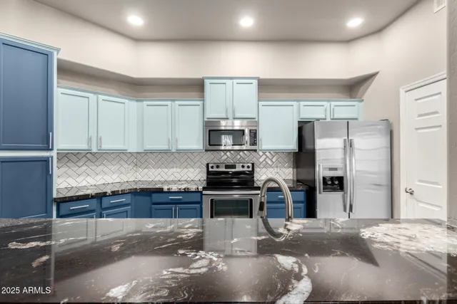 a kitchen with stainless steel appliances granite countertop a stove top oven a sink dishwasher a refrigerator and cabinets with wooden floor