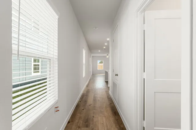 a view of a hallway with wooden floor and windows