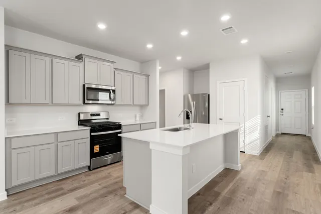 a kitchen with appliances a sink and cabinets