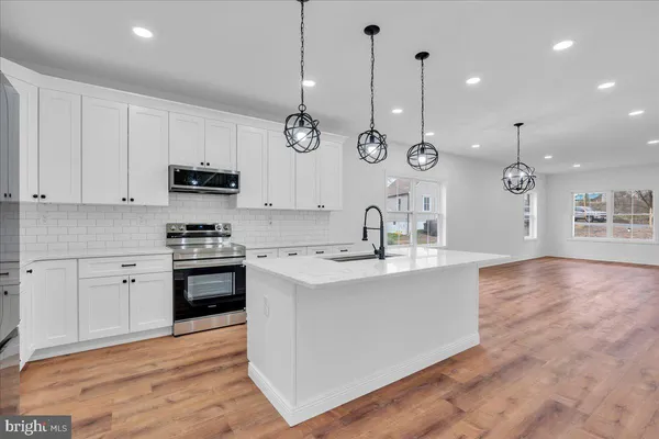 a kitchen with stainless steel appliances kitchen island a white cabinets and a wooden floor