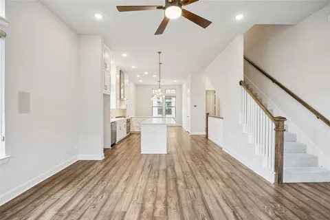 a view of a living room with wooden floor and a ceiling fan