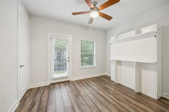 an empty room with wooden floor chandelier fan and windows
