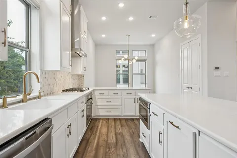 a large white kitchen with a large window a sink and cabinets