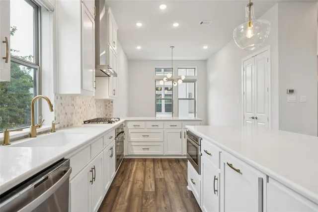 a large white kitchen with a large window a sink and cabinets