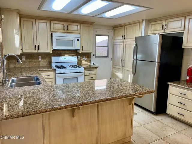 a kitchen with stainless steel appliances granite countertop a refrigerator a stove and a sink
