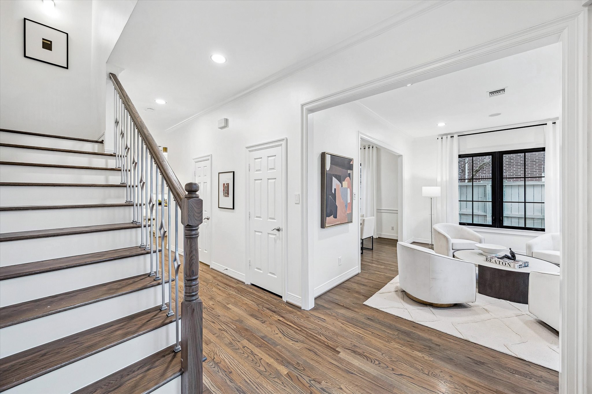 4122 Rice Boulevard West University Place, TX 77005 - Photo 13 of 30 Foyer with hardwood floors, crown molding, and staircase with iron balusters, opening to a light-filled formal living space. Upstairs has Primary bedroom with sitting room/bar + 3 secondary bedrooms + study.