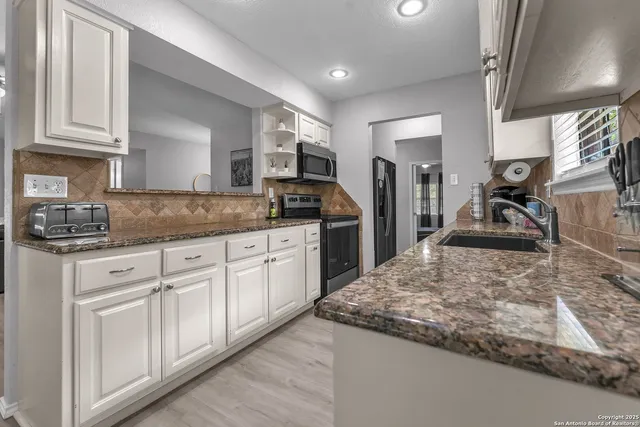 a kitchen with stainless steel appliances granite countertop a sink stove and cabinets