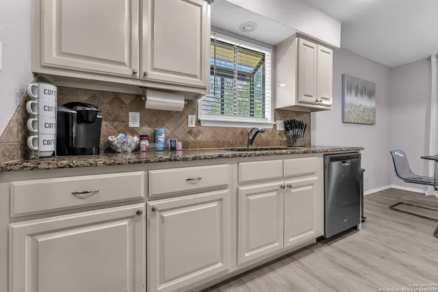 a kitchen with white cabinets and sink
