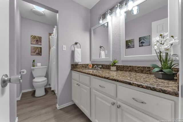 a bathroom with a granite countertop sink a toilet and a mirror