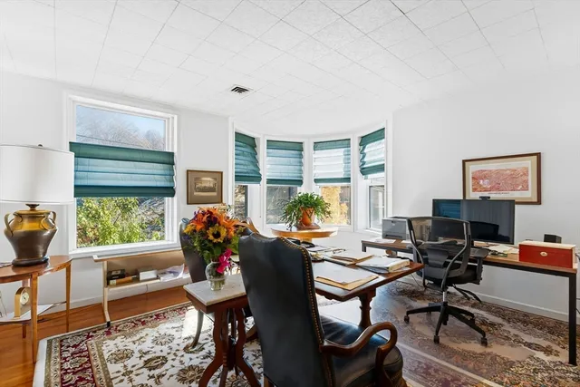a work room with furniture a rug and a window