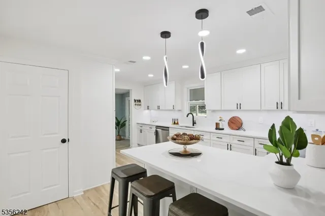 a kitchen with a sink a white cabinetry and chairs