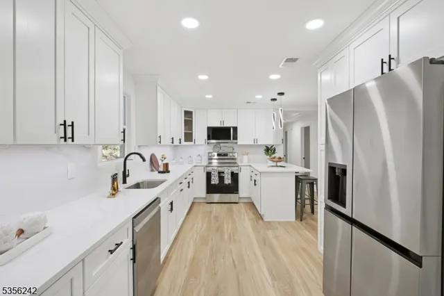 a kitchen with stainless steel appliances a refrigerator sink and white cabinets