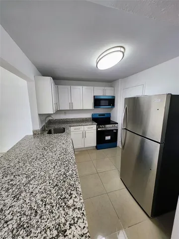 a kitchen with a refrigerator and a stove top oven