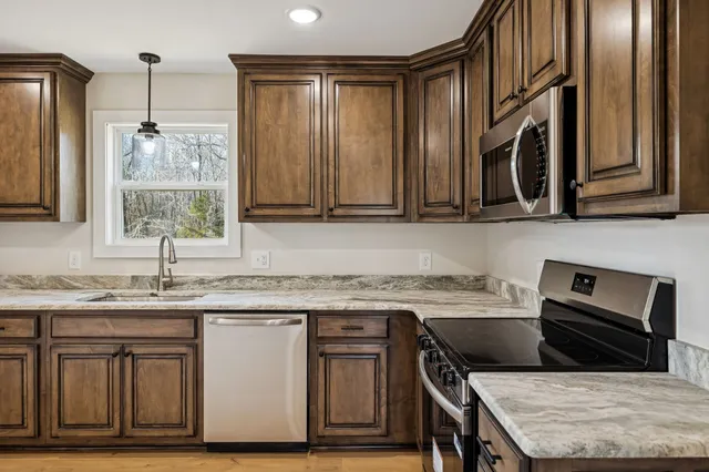 a kitchen with stainless steel appliances granite countertop a stove a sink and a microwave