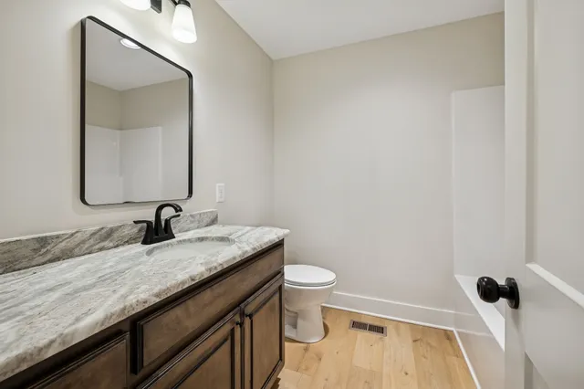 a bathroom with a granite countertop sink a toilet and a mirror