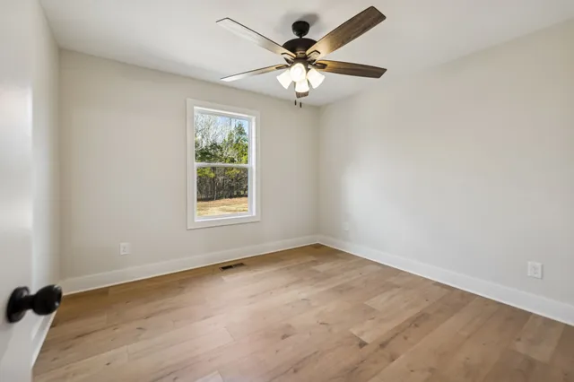 an empty room with a chandelier fan and windows