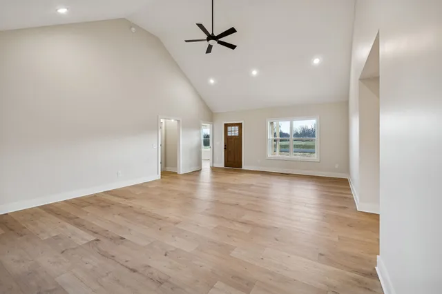 an empty room with wooden floor ceiling fan and windows