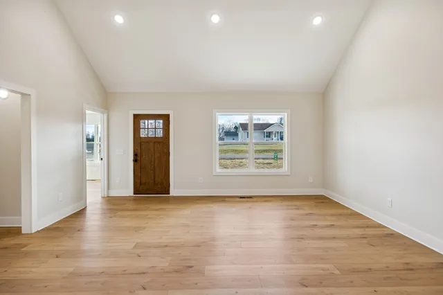 an empty room with wooden floor and windows