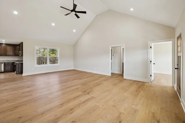 an empty room with wooden floor a ceiling fan and windows
