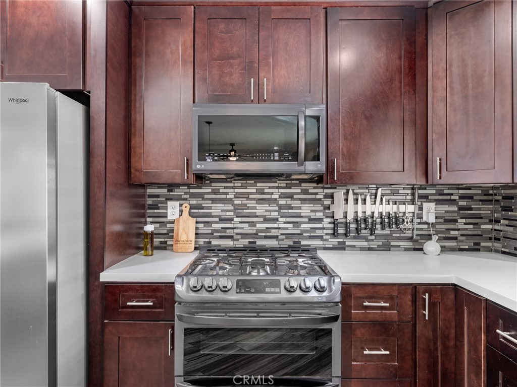 15485 Chole Road Apple Valley, CA 92307 - Photo 17 of 60 a kitchen with stainless steel appliances wooden cabinets and a stove top oven
