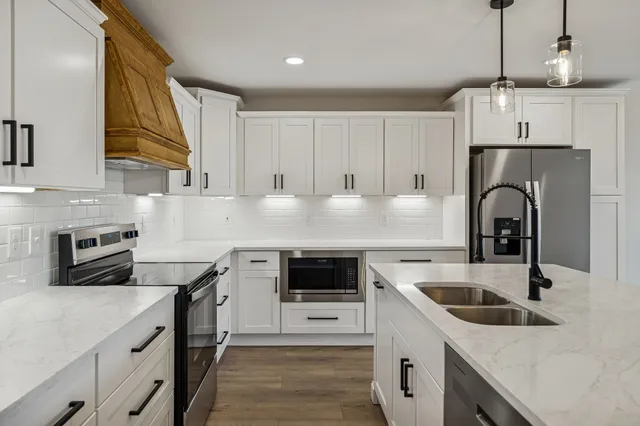a kitchen with granite countertop a sink stove and refrigerator