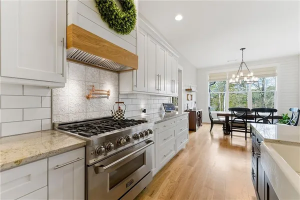 a large white kitchen with a large window a sink and a stove