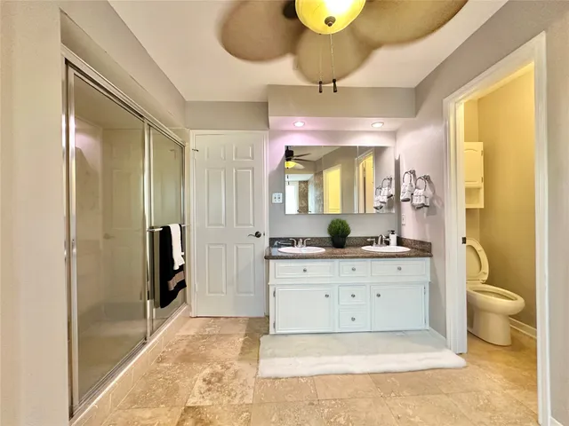 a spacious bathroom with a granite countertop sink a toilet a mirror and shower