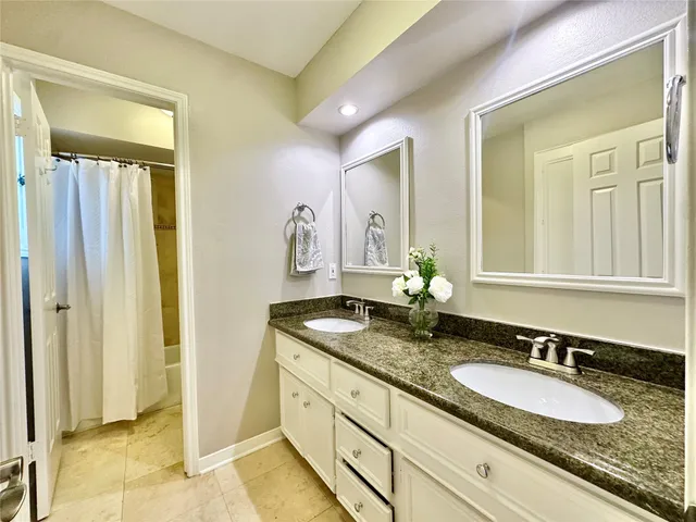 a bathroom with a granite countertop double vanity sink and a mirror