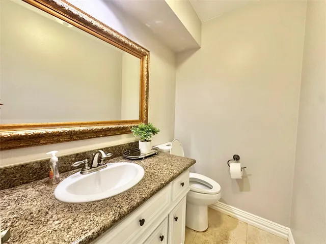 a bathroom with a granite countertop sink toilet and a mirror