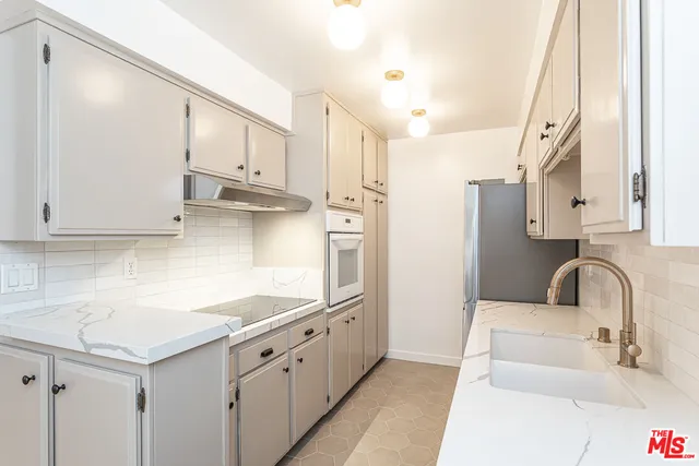 a kitchen with stainless steel appliances granite countertop a sink and white cabinets