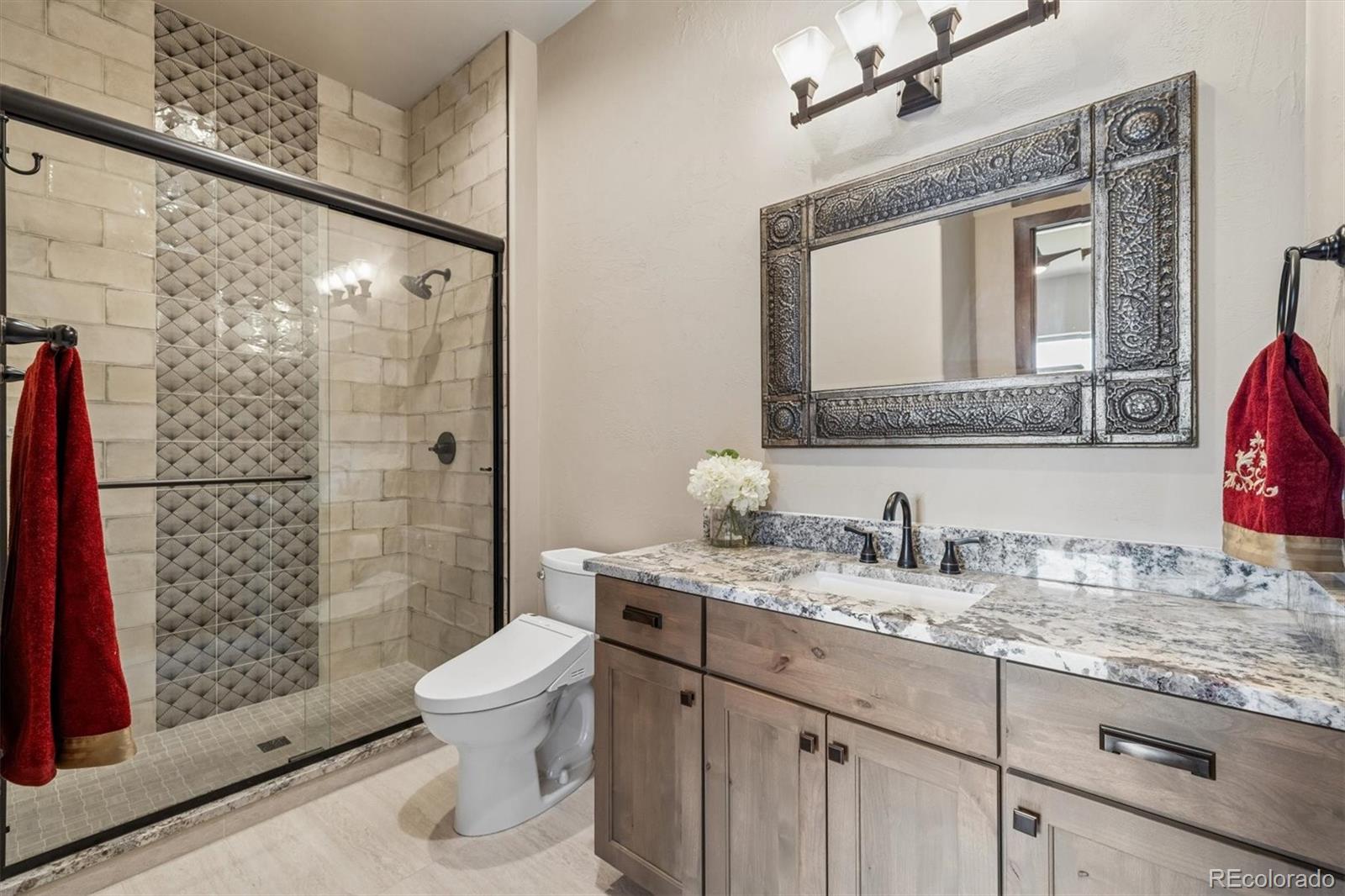 5754 Powell Road Parker, CO 80134 - Photo 27 of 43 a bathroom with a granite countertop sink a toilet and shower