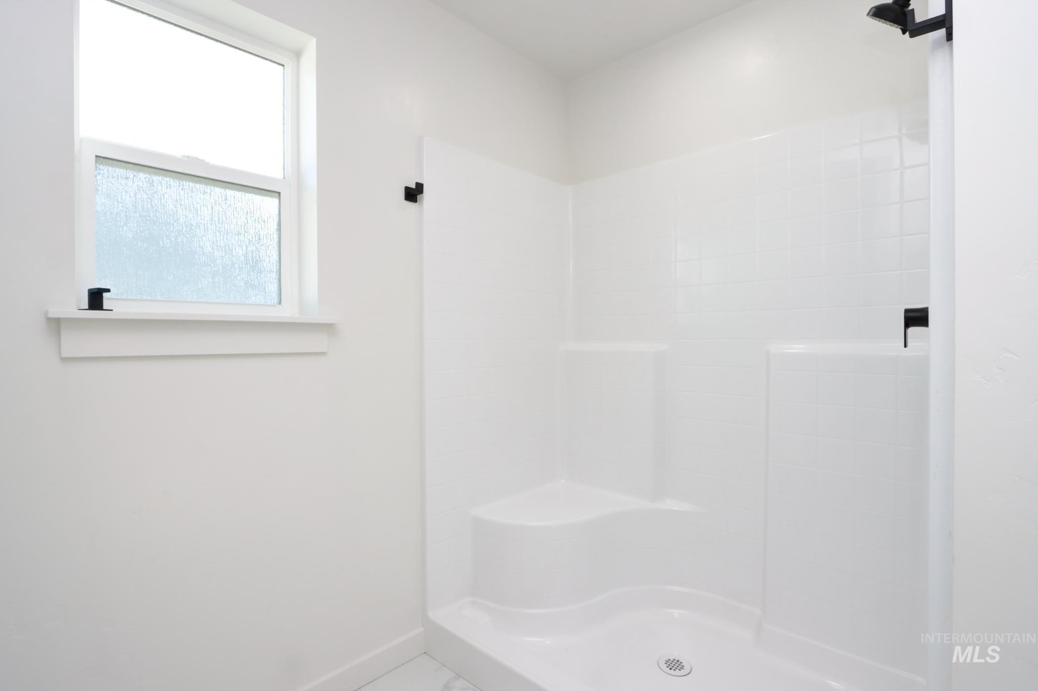 848 North 5th Street Nyssa, OR 97913 - Photo 23 of 49 Shower enclosure with integrated seating, white tile-patterned surround, matte black fixtures, and a frosted glass window