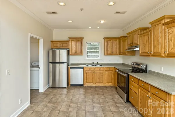 a kitchen with granite countertop a refrigerator and a stove top oven