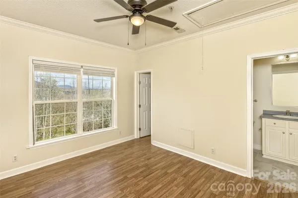 an empty room with wooden floor fan and windows