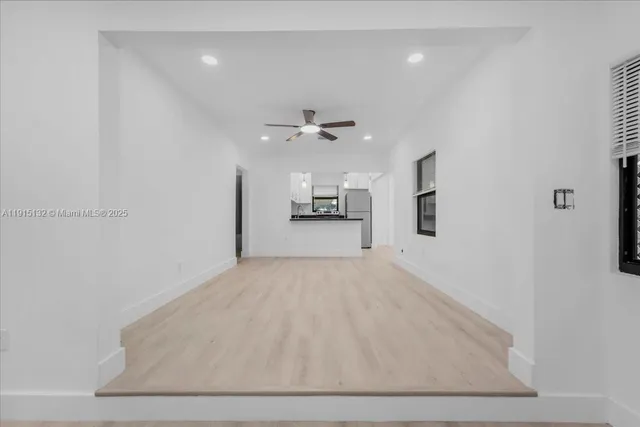 an empty room with large window and ceiling fan