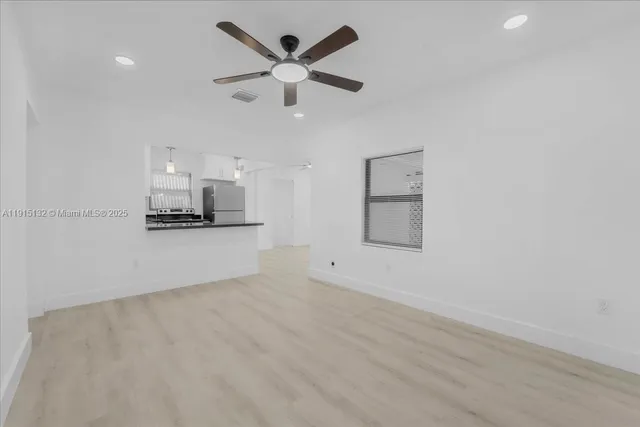 an empty room with a kitchen and a ceiling fan