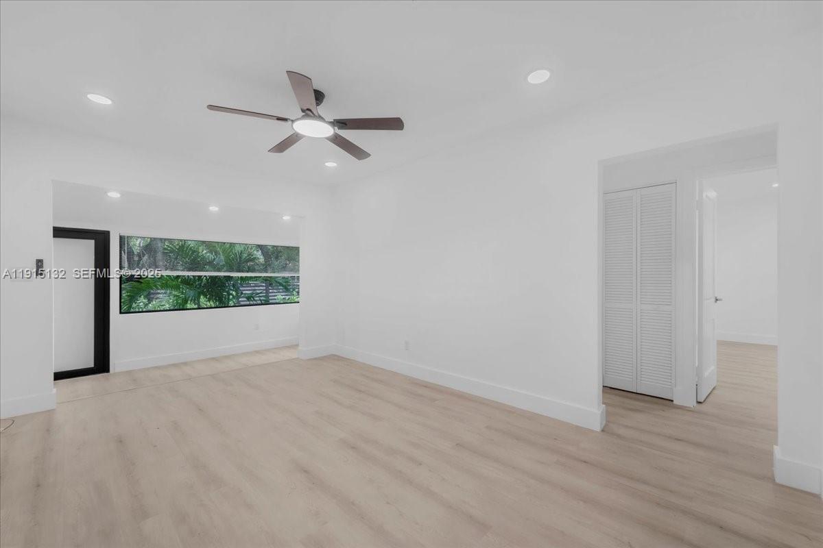 5220 Southwest 6th Street Miami, FL 33134 - Photo 28 of 56 an empty room with wooden floor fan and a kitchen view