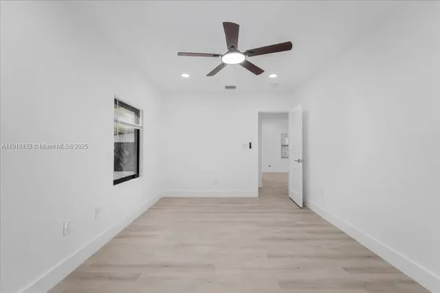 an empty room with a ceiling fan and window