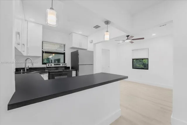 a open kitchen with white cabinets and stainless steel appliances