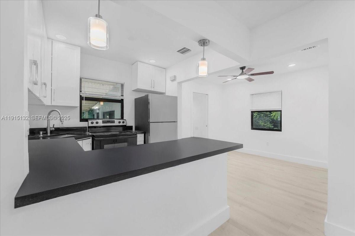 5220 Southwest 6th Street Miami, FL 33134 - Photo 44 of 56 a kitchen with stainless steel appliances granite countertop a refrigerator a sink dishwasher a stove and white countertops with wooden floor