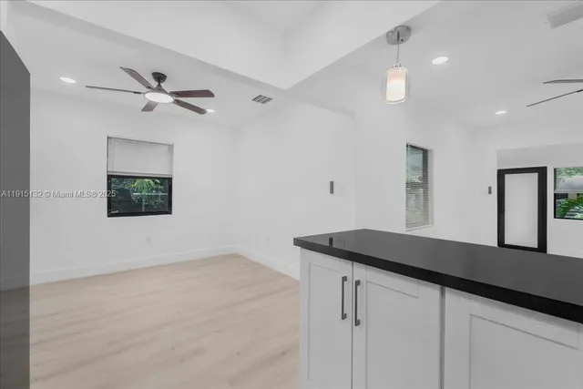 a view of an empty room with wooden floor and windows