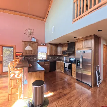 a kitchen with a refrigerator a stove and a sink with wooden floor