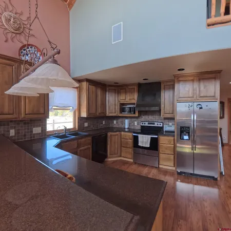 a kitchen with stainless steel appliances granite countertop a refrigerator a stove a sink dishwasher a dining table and chairs with wooden floor