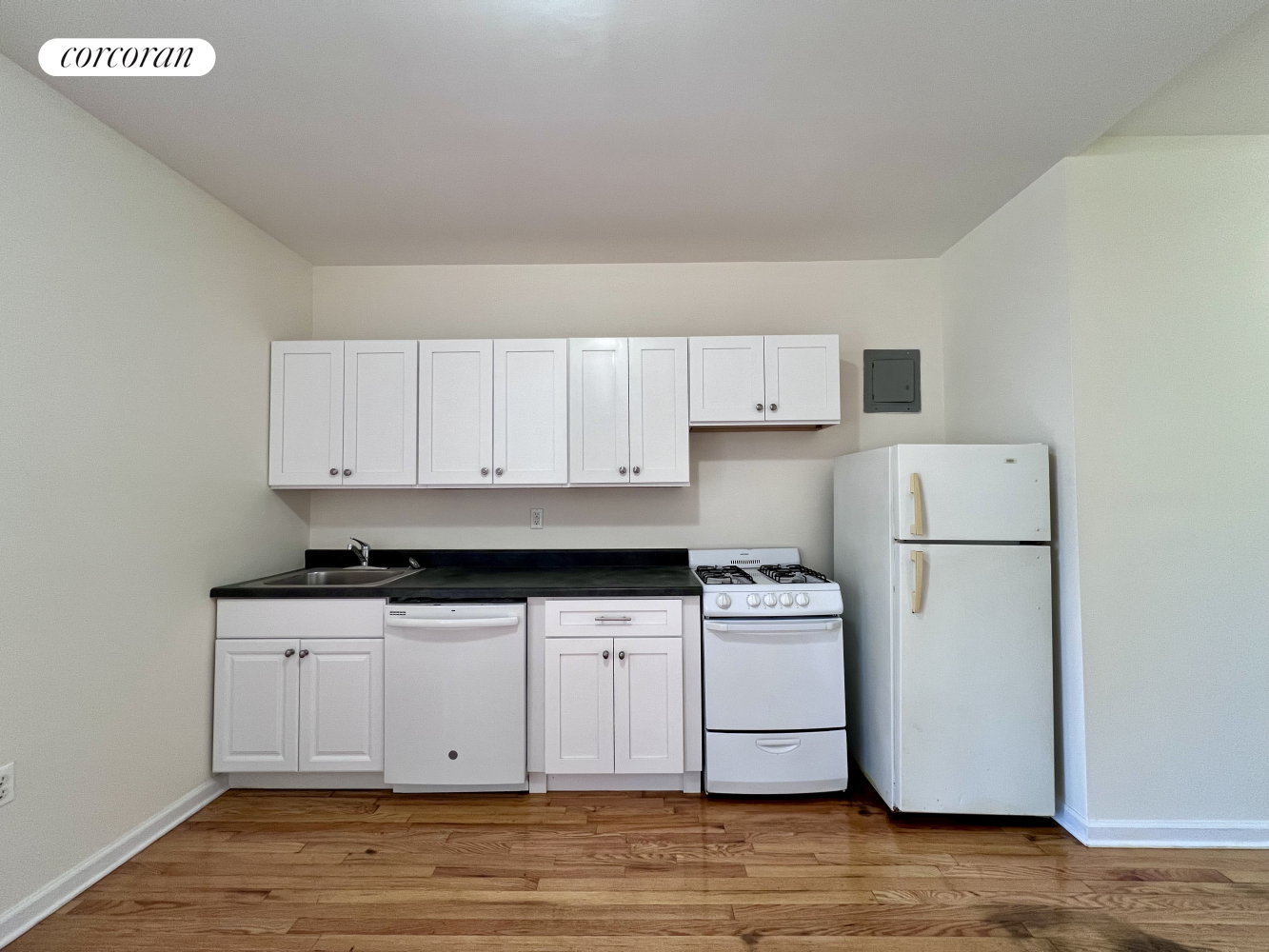 a kitchen with granite countertop a white refrigerator oven a white cabinets and a sink