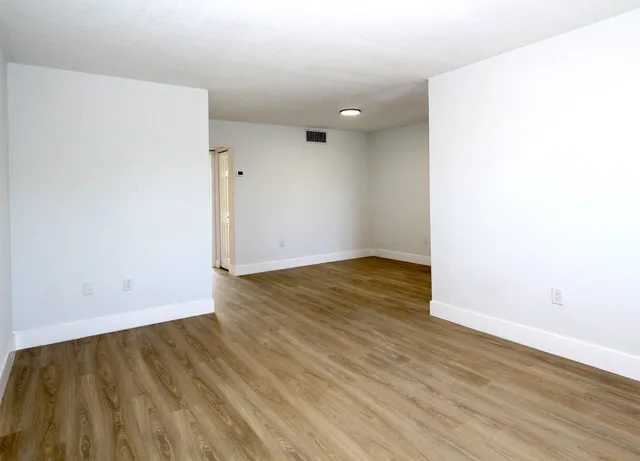 an empty room with wooden floor and white walls