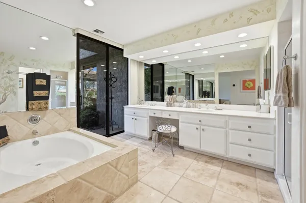 a spacious bathroom with a double vanity sink mirror and bathtub