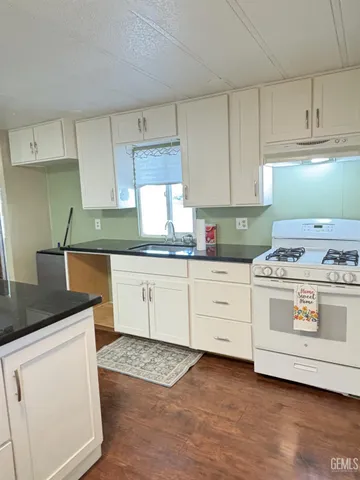 a kitchen with granite countertop white cabinets and white appliances